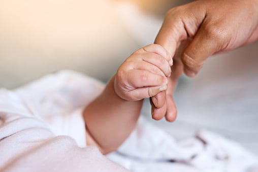 close up of baby's hand holding parent's finger