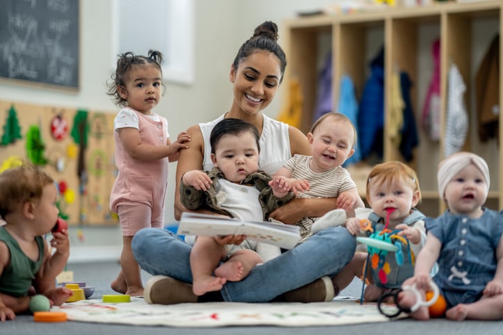 Day care provider reading to children all sitting around on floor